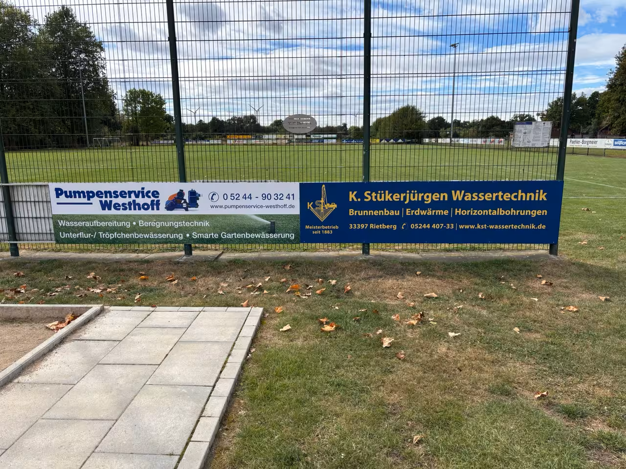 Werbebanner am Spielfeldrand – zwei Sponsorenbannner an der Umzäunung des Sportplatzes.