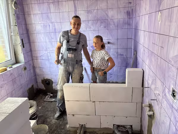 Vater und Tochter vor der frisch gemauerten Wand.