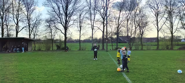 Bambini-Kinder stehen in einer Reihe auf dem Trainingsplatz und üben den Einwurf-Weitwurf mit dem Fußball.