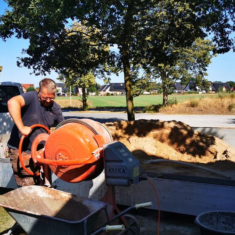 Ehrenamtlicher Helfer mischt Beton für den Umbau der Schiedsrichterkabine